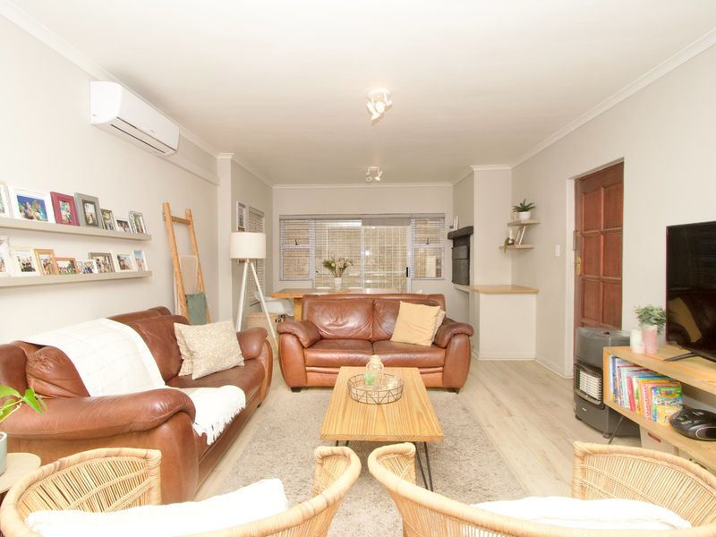 A well-maintained living room featuring laminate flooring, a split-system air conditioner, and a built-in fireplace, offering a comfortable and functional living space.