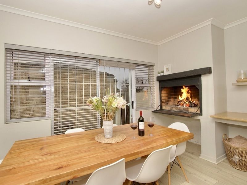 A bright dining room featuring a built-in fireplace, tiled flooring, and large sliding glass doors with venetian blinds providing natural light.
