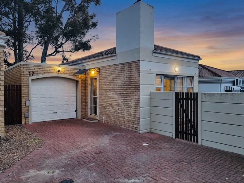 Front elevation of a brick-faced house featuring a single garage, paved driveway, and secure gated entrance.