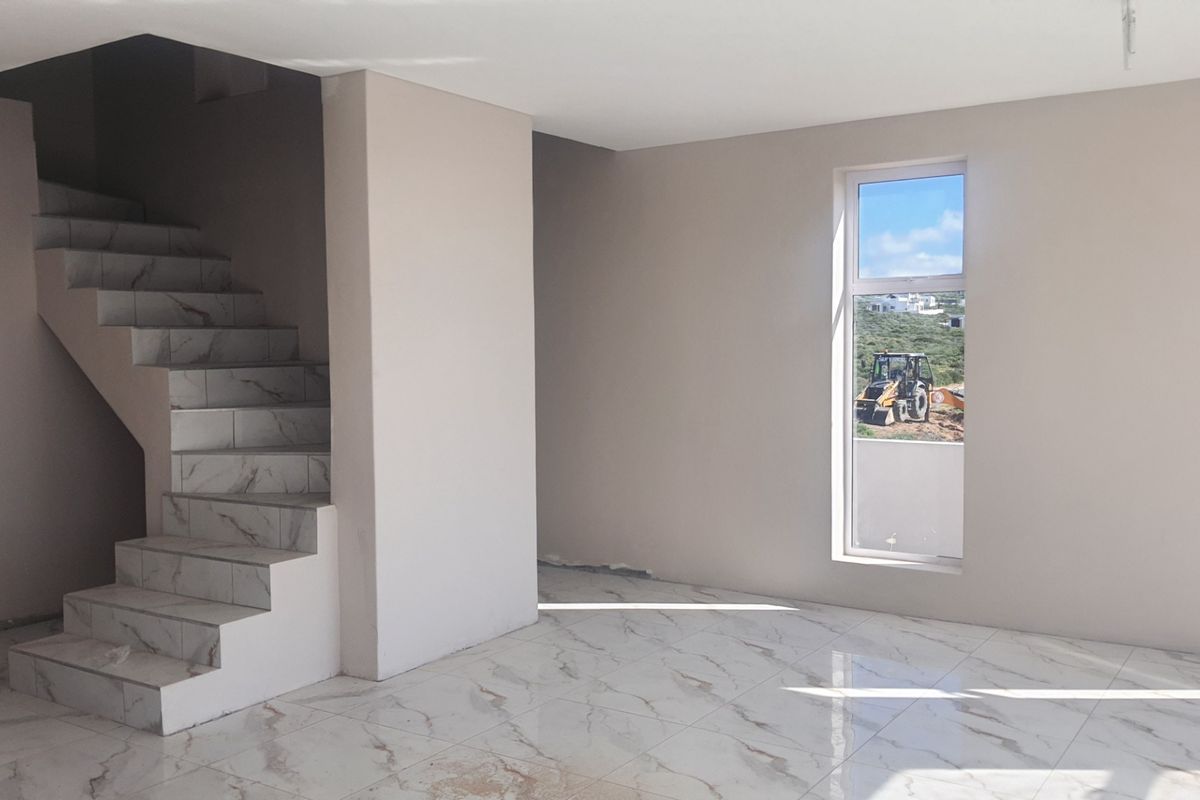 An open-plan living area featuring modern marble-look floor tiles and a matching tiled staircase, currently in a near-finished state.