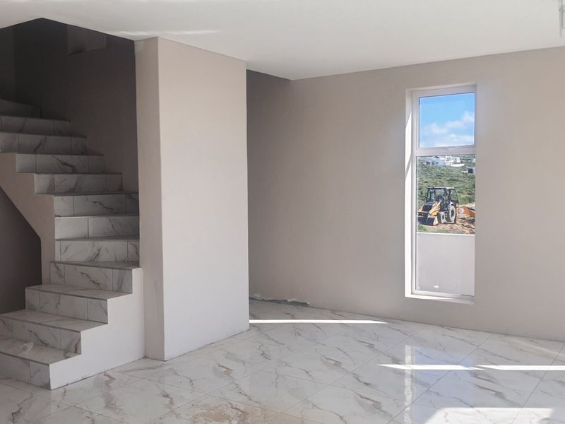 An open-plan living area featuring modern marble-look floor tiles and a matching tiled staircase, currently in a near-finished state.