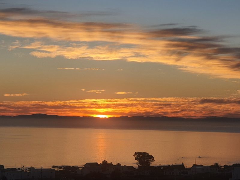 A scenic sunset view overlooking the ocean and coastal landscape, highlighting the property's elevated position and natural surroundings.