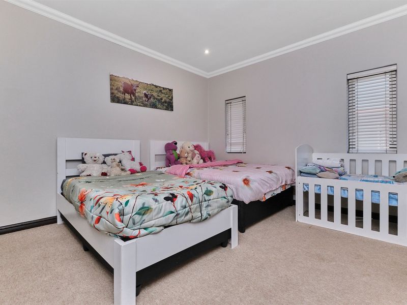 A spacious bedroom featuring neutral wall tones, carpeted flooring, recessed downlighting, and venetian blinds on the windows.