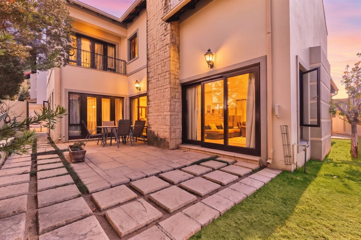 Rear view of the property featuring a paved patio area, stone-clad chimney, and sliding glass doors leading into the living space.