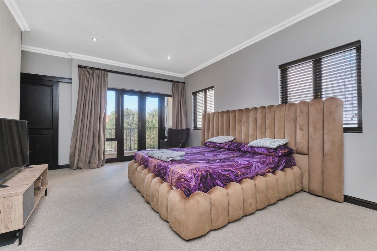 Spacious bedroom featuring neutral carpeting, recessed downlighting, crown molding, and direct access to a private balcony through sliding glass doors.