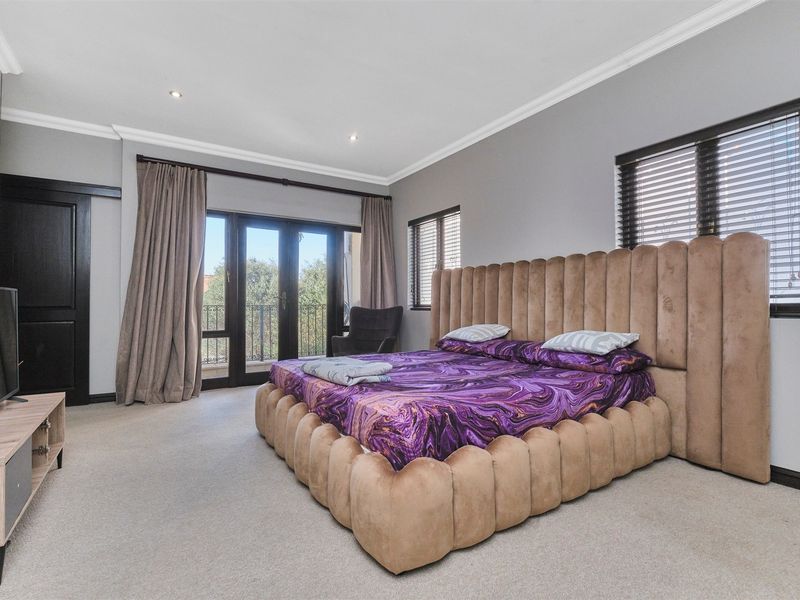 Spacious bedroom featuring neutral carpeting, recessed downlighting, crown molding, and direct access to a private balcony through sliding glass doors.