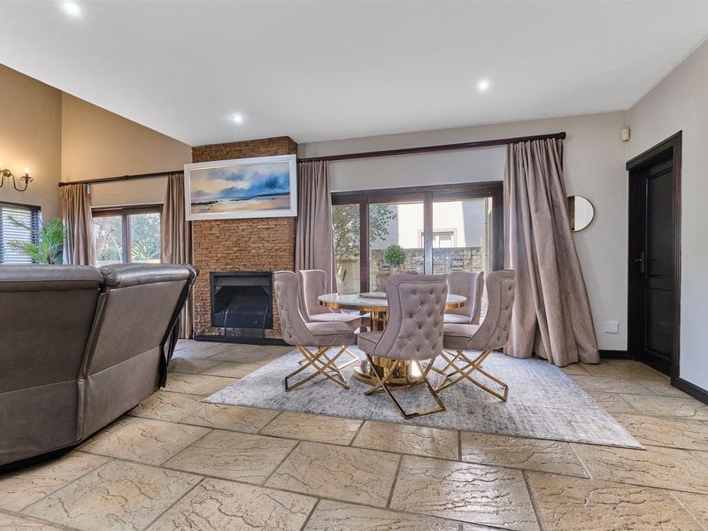 Spacious living area featuring stone tile flooring, a prominent stone-clad fireplace, and large sliding glass doors providing access to the outdoor space.