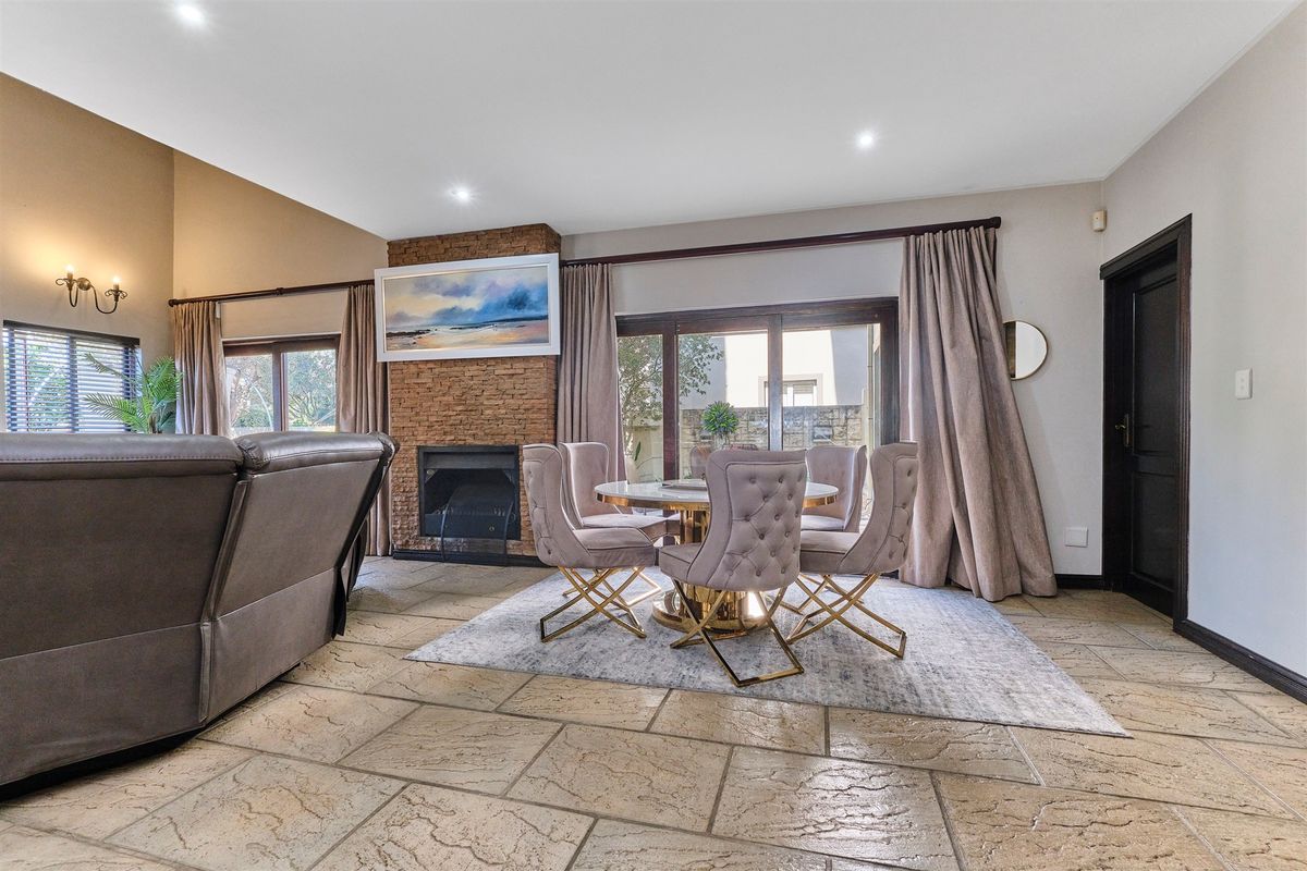 Spacious living area featuring stone tile flooring, a prominent stone-clad fireplace, and large sliding glass doors providing access to the outdoor space.
