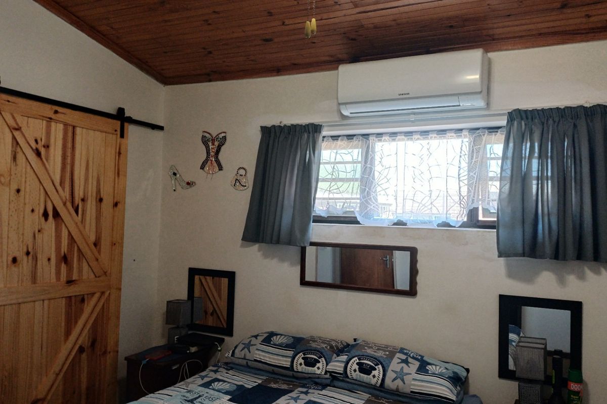 A bedroom featuring a timber ceiling, a sliding barn door, and a wall-mounted split-system air conditioner.