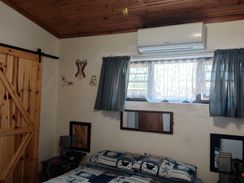 A bedroom featuring a timber ceiling, a sliding barn door, and a wall-mounted split-system air conditioner.