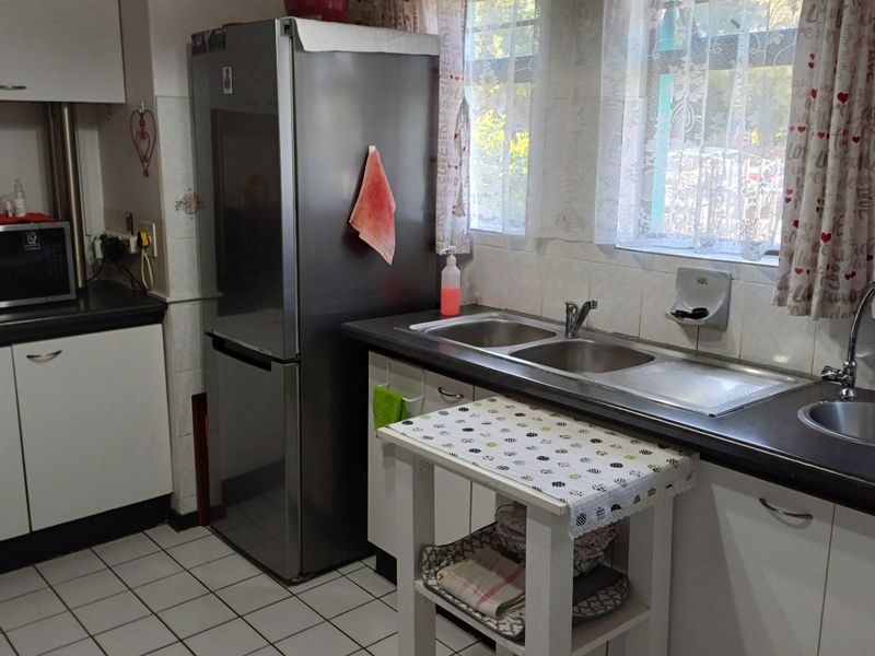 A functional kitchen featuring dual sink areas, laminate countertops, tiled backsplash, and white cabinetry with tiled flooring.
