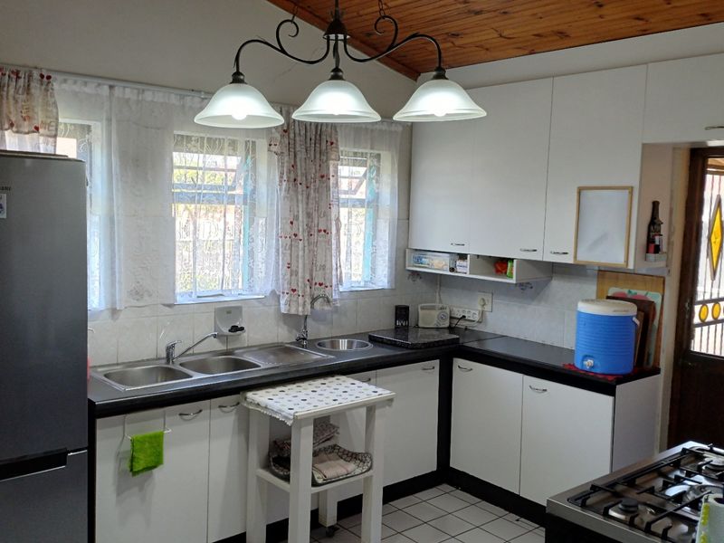 Functional kitchen featuring white cabinetry, laminate countertops, a double bowl sink, and a timber ceiling, providing a practical workspace.