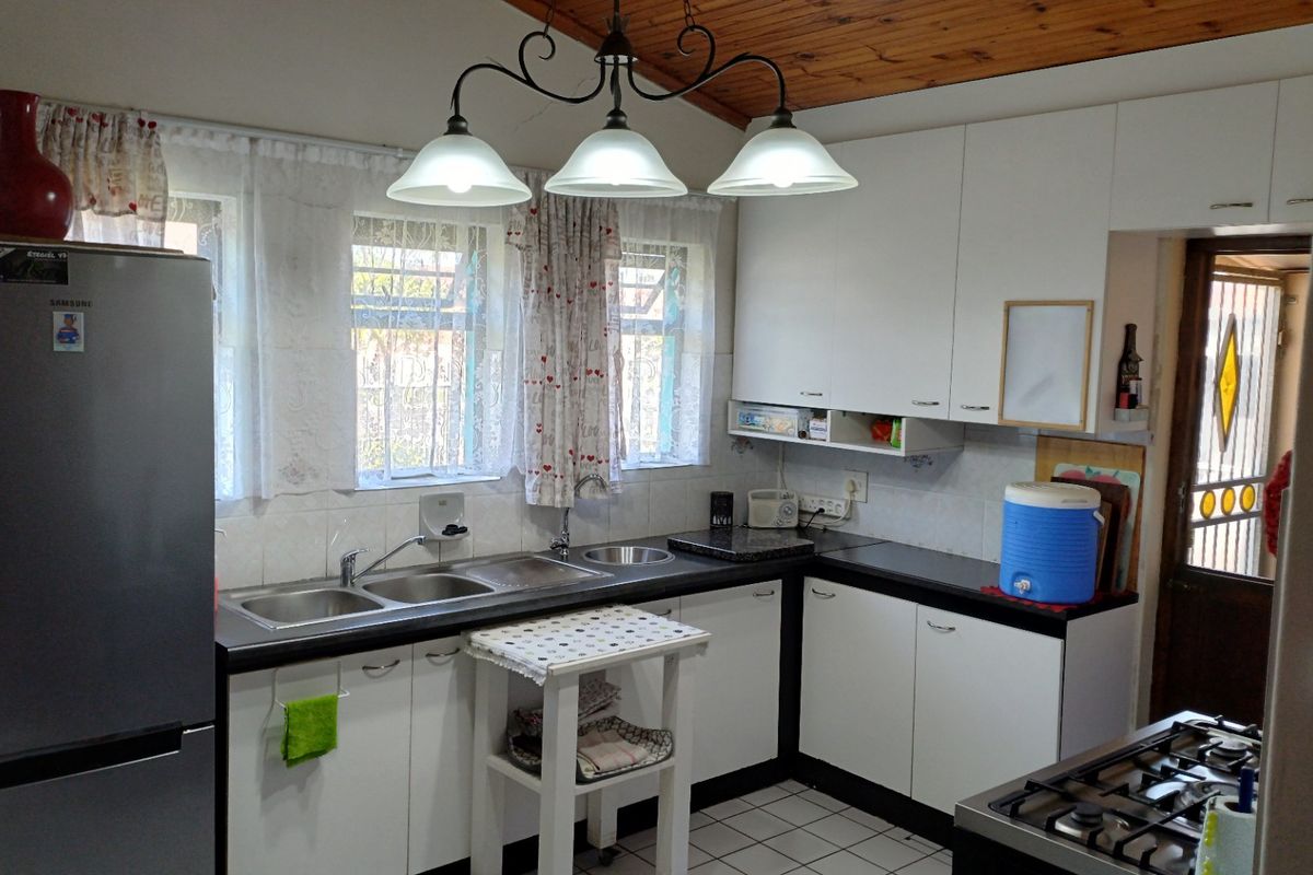 Functional kitchen featuring white cabinetry, laminate countertops, a double bowl sink, and a timber ceiling, providing a practical workspace.