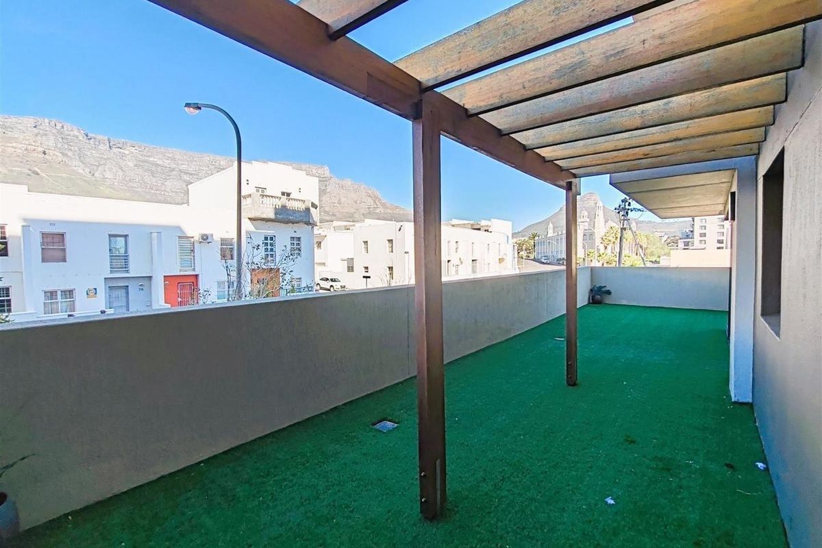 Spacious balcony featuring a timber pergola structure, concrete balustrade, and artificial turf flooring with mountain views.