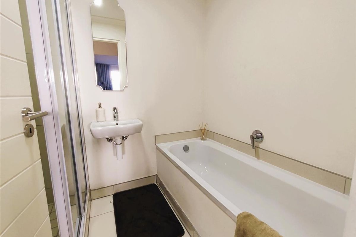 A clean, functional bathroom featuring a shower enclosure, a wall-mounted basin, and a bathtub with modern fixtures.