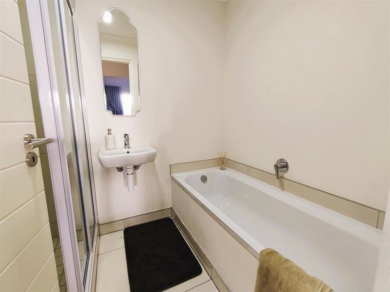 A clean, functional bathroom featuring a shower enclosure, a wall-mounted basin, and a bathtub with modern fixtures.