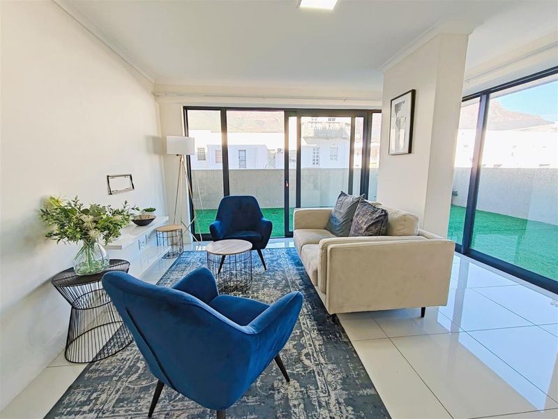 Bright living room featuring large sliding glass doors that provide access to an outdoor area, complemented by modern tiled flooring and neutral finishes.