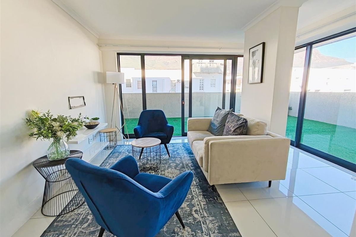 Bright living room featuring large sliding glass doors that provide access to an outdoor area, complemented by modern tiled flooring and neutral finishes.
