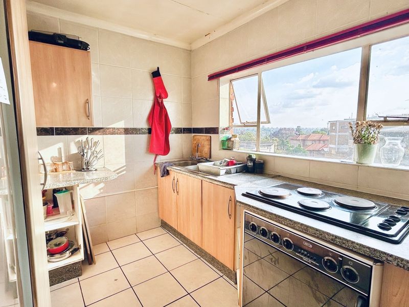 A functional kitchen featuring built-in cabinetry, laminate countertops, an electric stove, and a large window providing natural light and an elevated view.