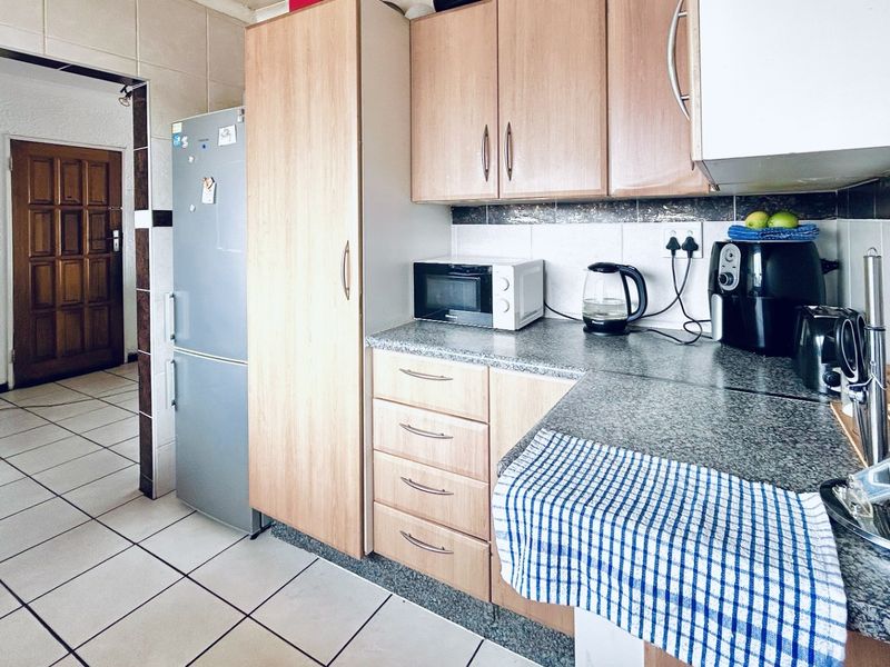 A functional kitchen featuring laminate cabinetry, granite countertops, and tiled flooring, providing a practical workspace with a neutral aesthetic.
