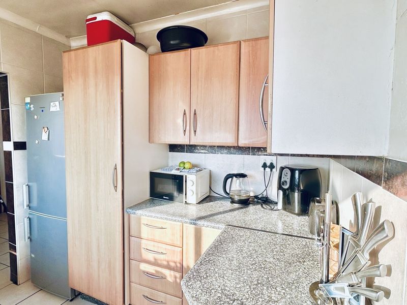 A functional kitchen featuring laminate cabinetry, granite countertops, and a tiled backsplash, offering a practical layout for daily meal preparation.