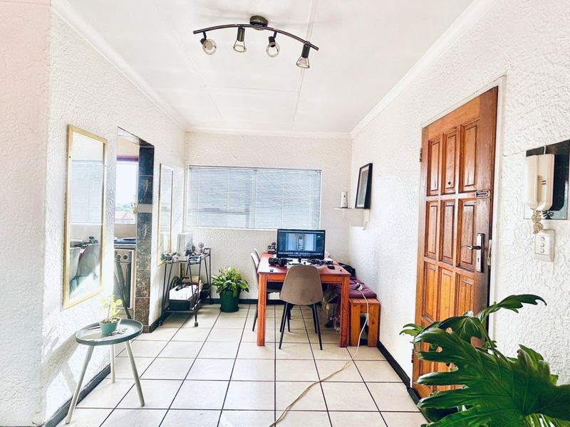 Entrance area featuring tiled flooring, textured walls, and a solid timber door, providing a functional transition space into the home.