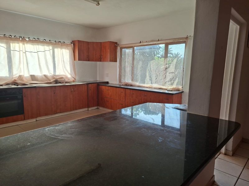 A spacious kitchen featuring dark granite countertops, wood-finish cabinetry, and an integrated oven, offering a functional layout ready for modern updates.