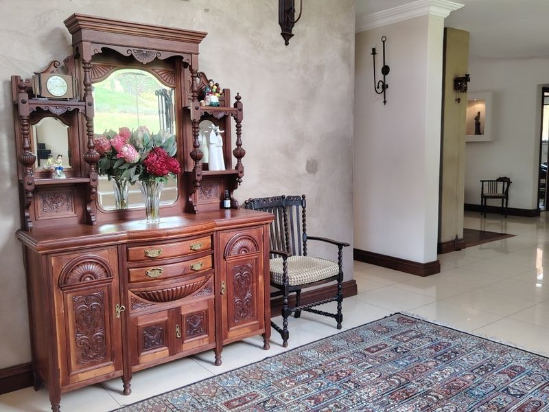 A spacious hallway featuring polished tiled flooring, neutral wall finishes, and decorative wall sconces, leading into the main living areas of the home.