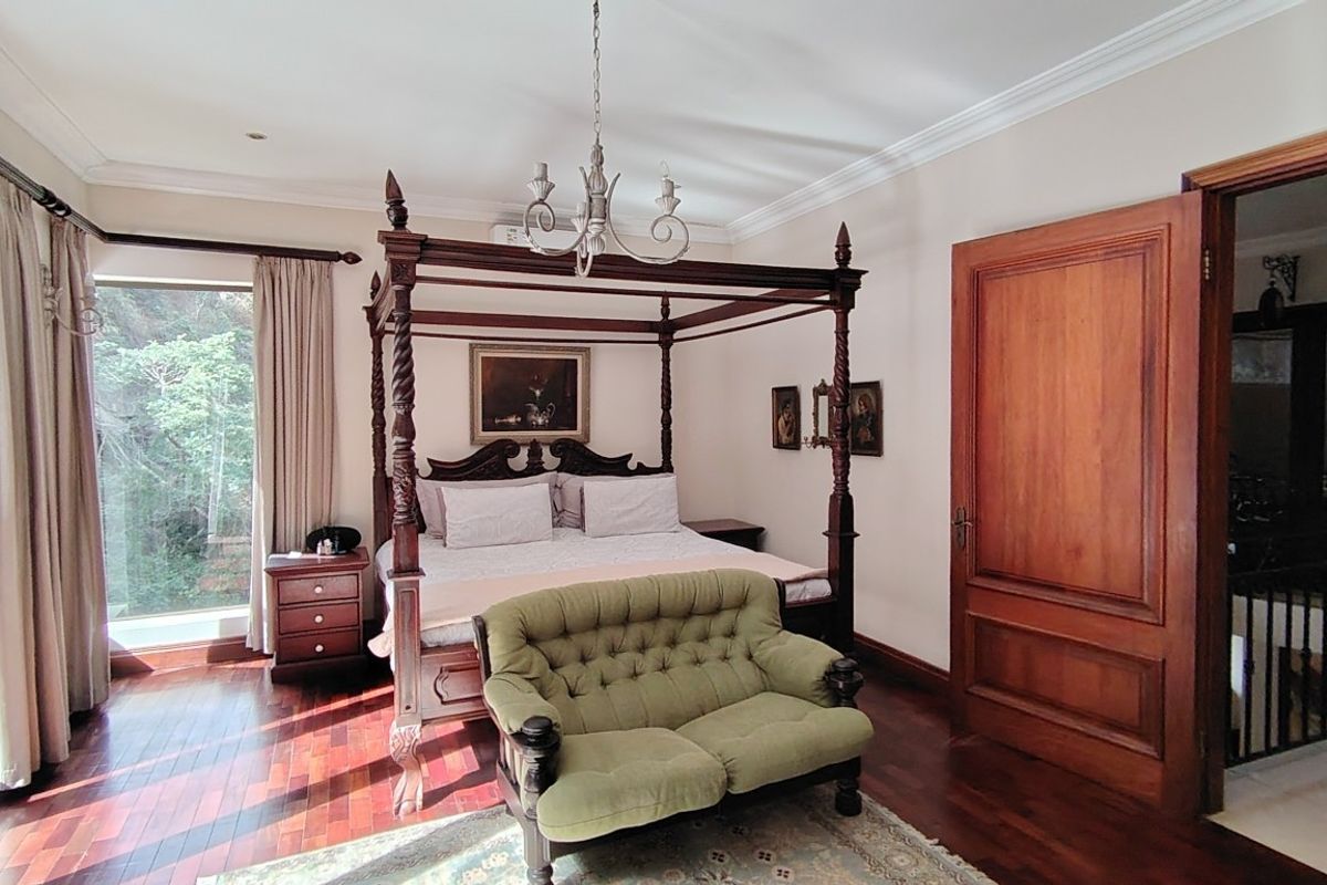 Spacious bedroom featuring rich hardwood flooring, crown molding, a classic chandelier, and large sliding glass doors providing natural light and outdoor access.