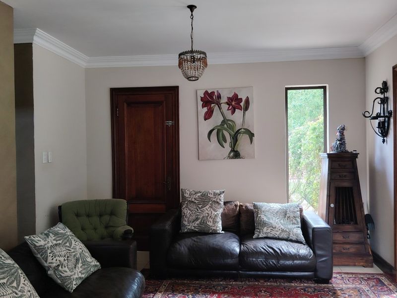 A cozy living room featuring crown molding, a classic pendant light, and access to the outdoors through a glass sliding door.