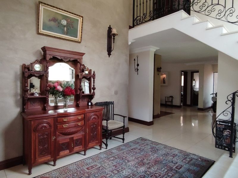 Spacious entrance hall featuring tiled flooring and an elegant staircase with decorative wrought iron railings, leading to the upper level of the home.