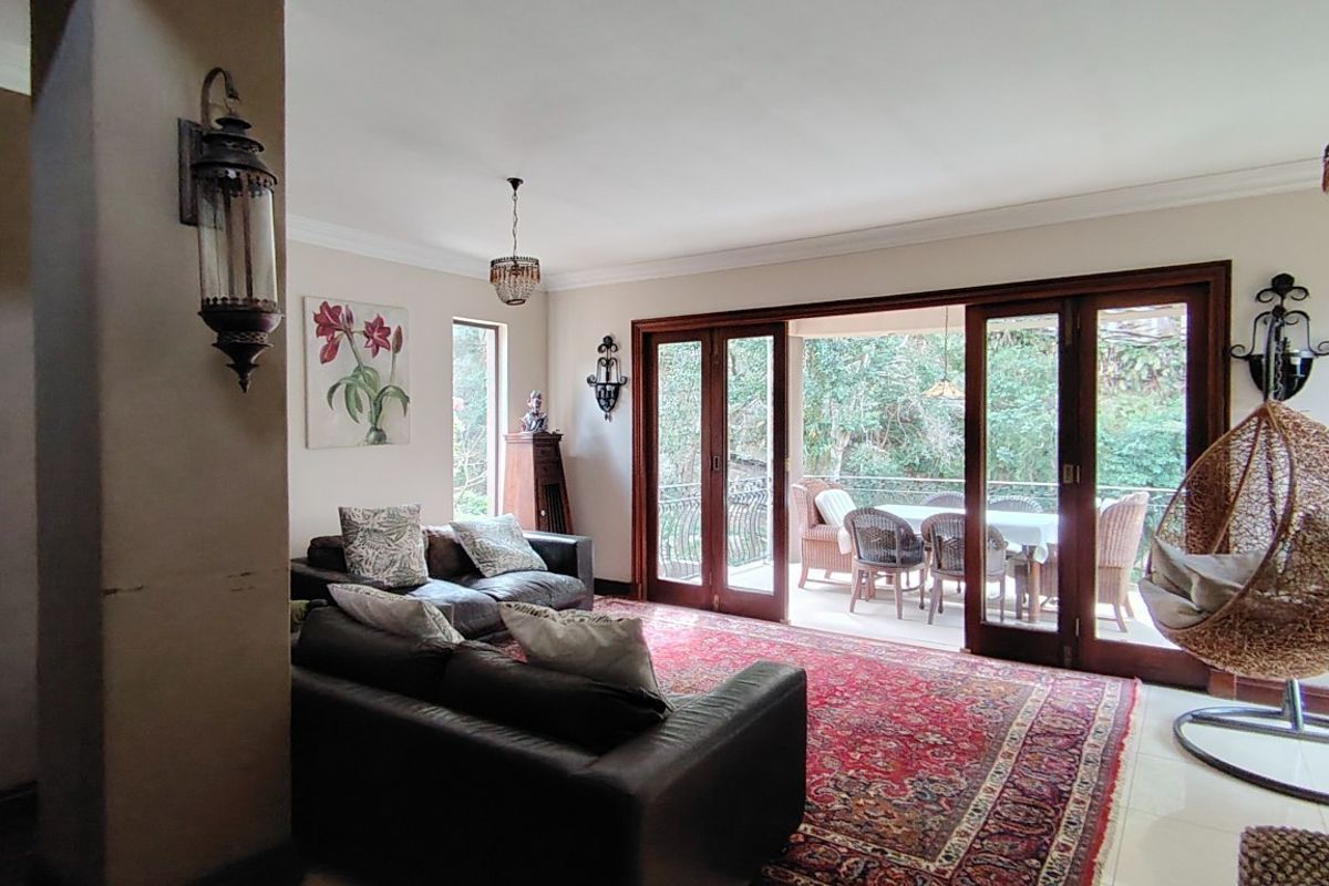 Spacious living room featuring tiled floors, decorative coving, and large wooden sliding doors that open onto an outdoor patio area.