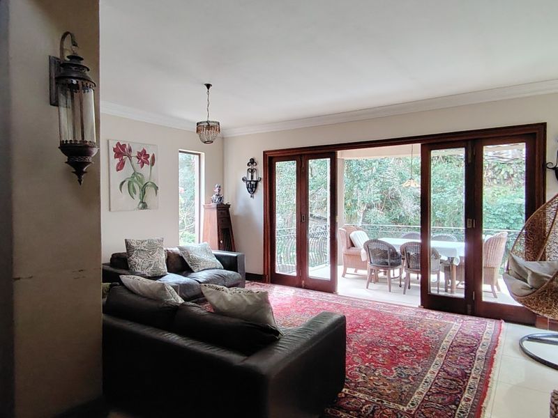 Spacious living room featuring tiled floors, decorative coving, and large wooden sliding doors that open onto an outdoor patio area.