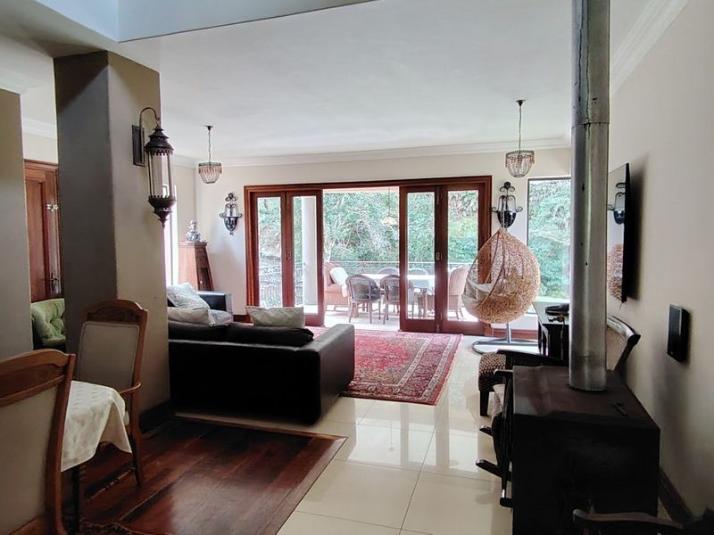 Spacious open-plan living area featuring a mix of tiled and hardwood flooring, a freestanding fireplace, and large sliding doors opening to an outdoor patio.