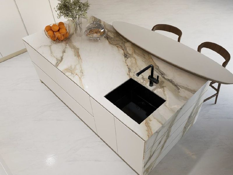 Modern kitchen island featuring a marble countertop, integrated black sink, and sleek handleless cabinetry in a bright, contemporary space.