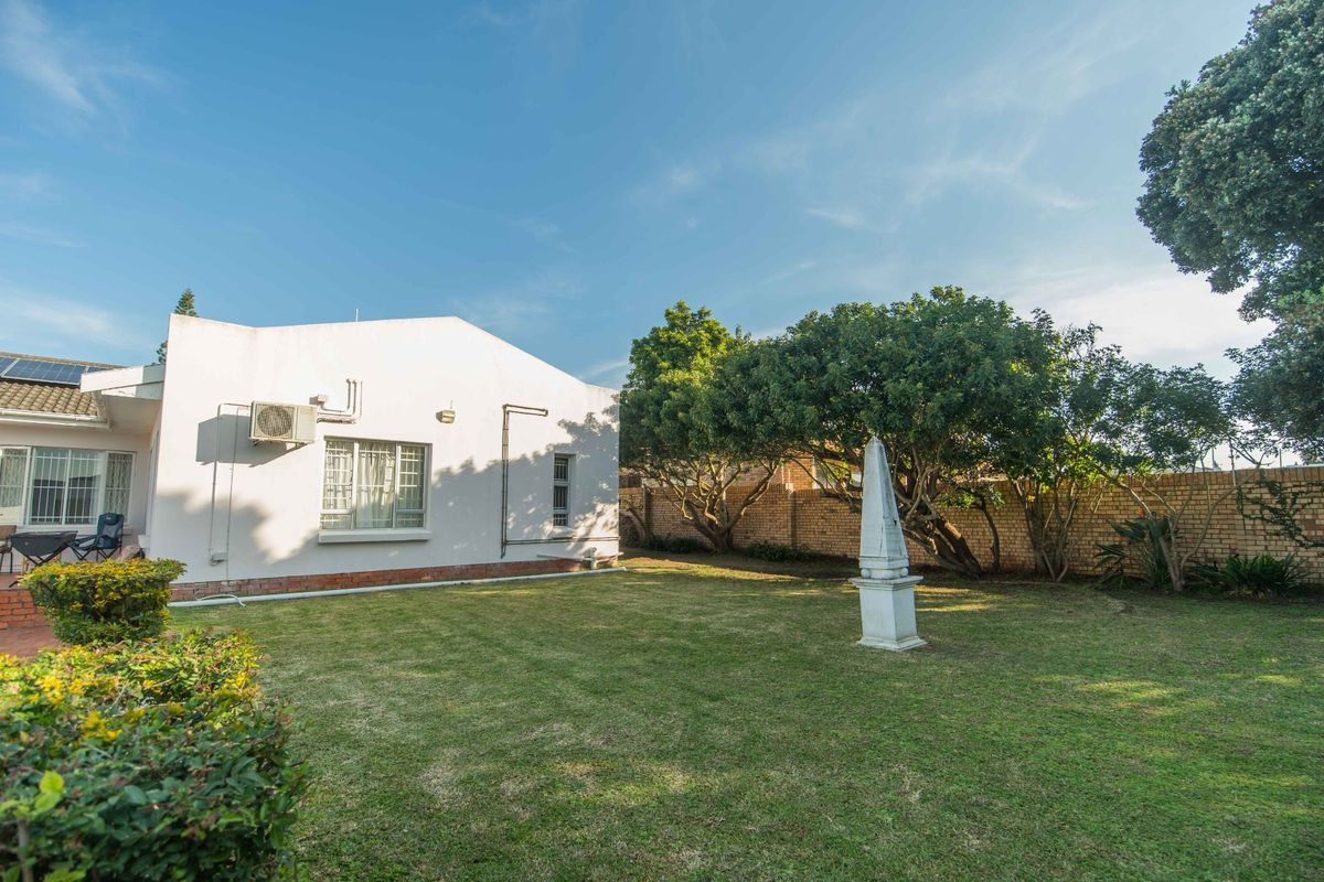 A well-maintained rear garden featuring a manicured lawn, mature trees, and a brick boundary wall, providing a private outdoor space.