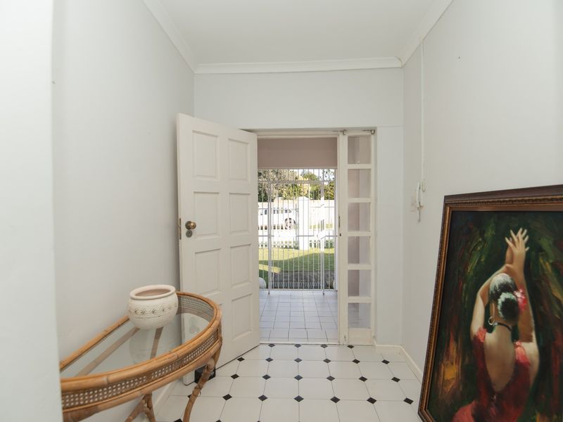 Entrance hall featuring classic black and white tiled flooring, leading through a panelled door to an outdoor security gate area.