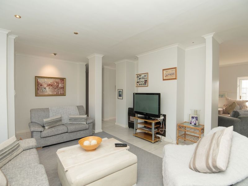 A neutrally painted living room featuring tiled flooring, recessed downlighting, and coved cornicing, offering a clean and functional space.