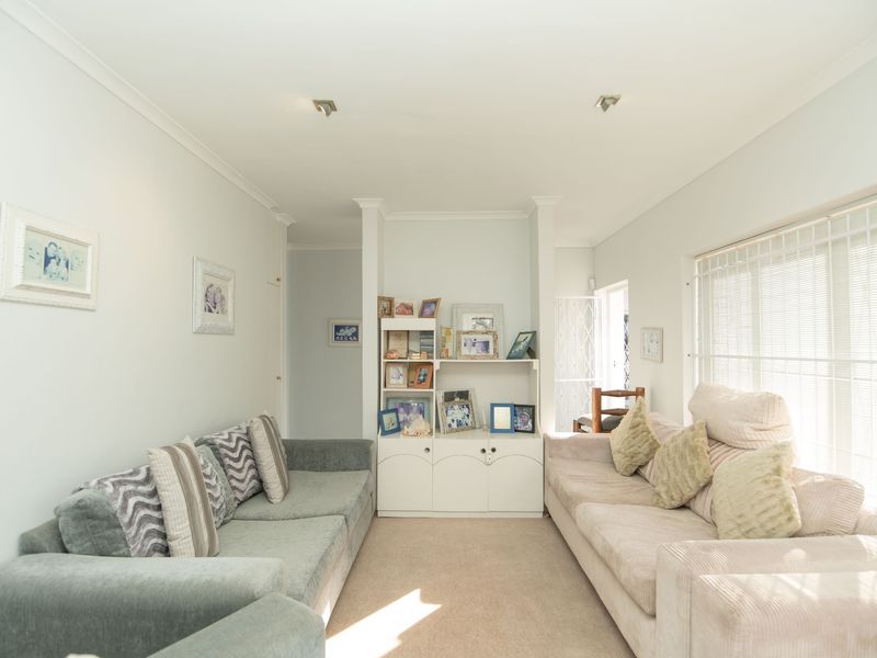A comfortable living room featuring neutral walls, carpet flooring, recessed lighting, and built-in cabinetry, offering a functional and well-lit space.