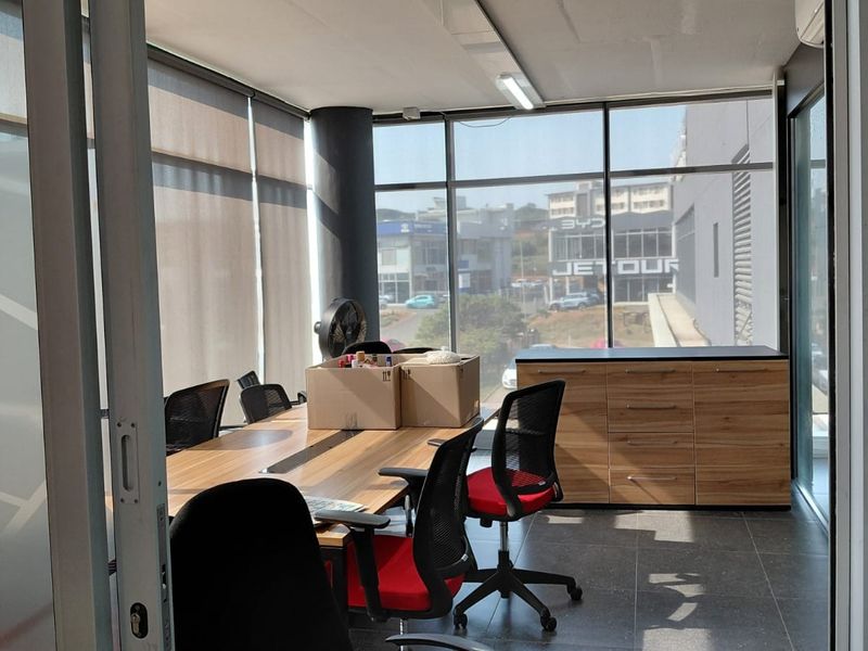 A bright office space featuring floor-to-ceiling windows with roller blinds, tiled flooring, and integrated built-in cabinetry.