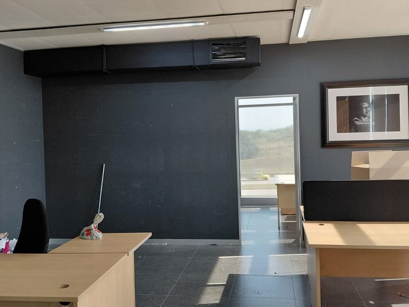 A functional office space featuring dark grey walls, tiled flooring, and exposed ceiling ducting, providing a professional environment for business operations.