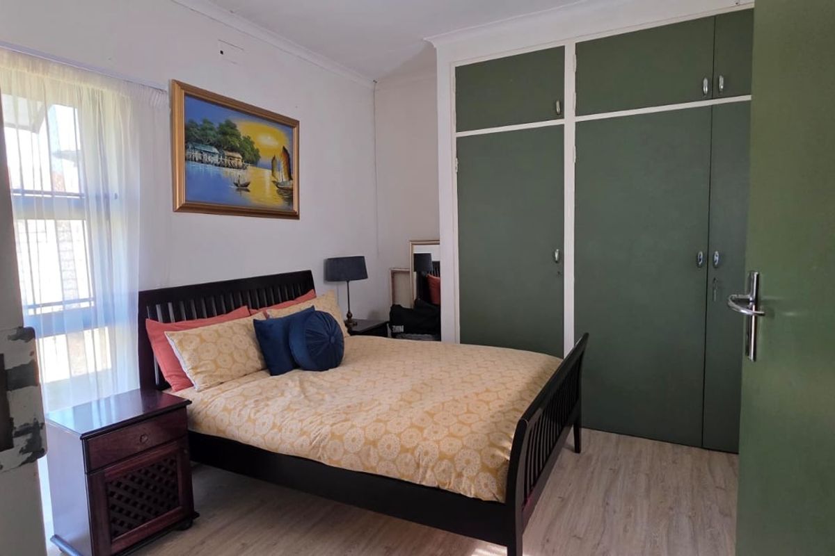 A bedroom featuring laminate flooring and floor-to-ceiling built-in cupboards with a green finish.