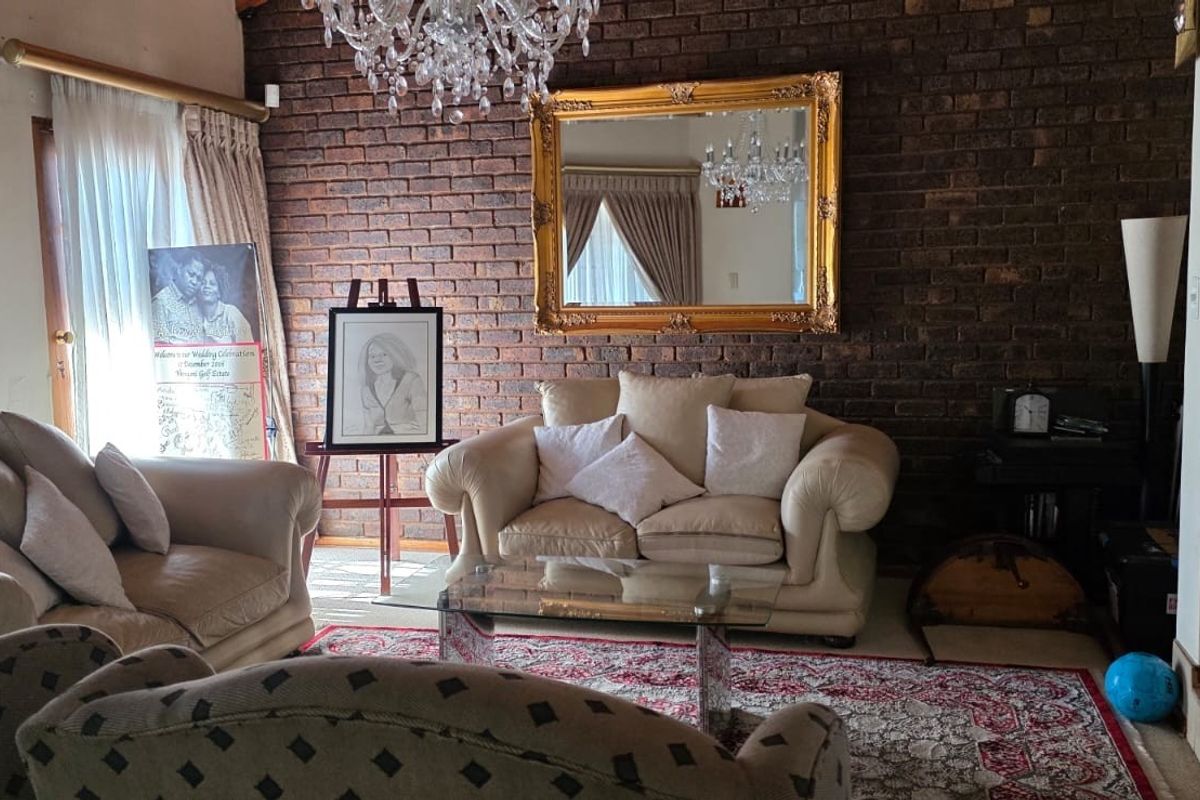 A cozy living room featuring a prominent exposed brick feature wall, vaulted ceilings, and an elegant crystal chandelier.