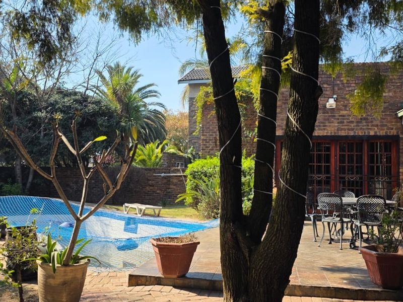 Rear garden area featuring a swimming pool with safety net, paved patio space, and face brick exterior wall.