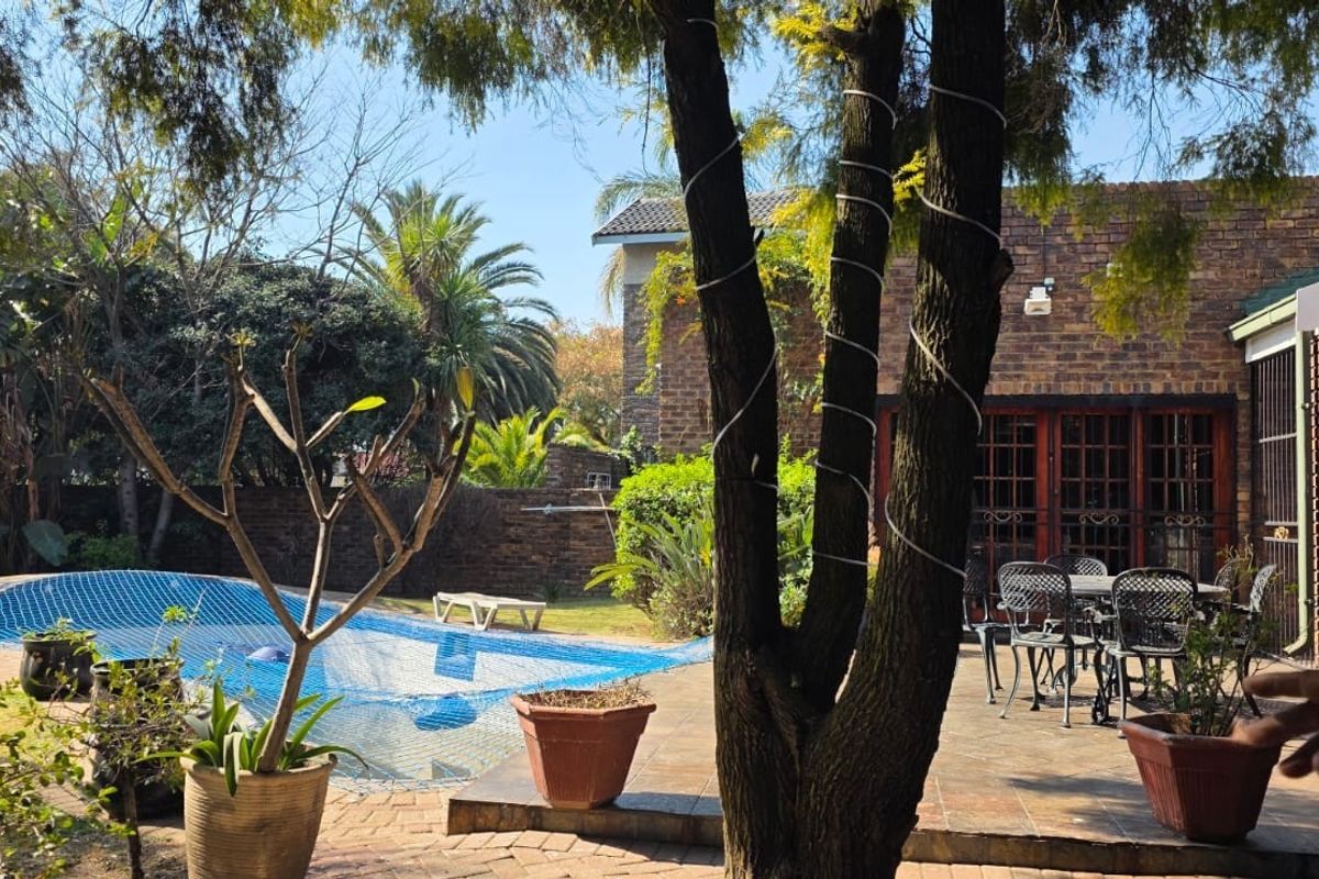 Rear garden area featuring a swimming pool with safety net, paved patio space, and face brick exterior wall.