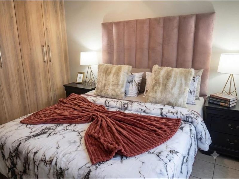 A well-maintained bedroom featuring a built-in wardrobe with wood-grain finish and a modern upholstered headboard.