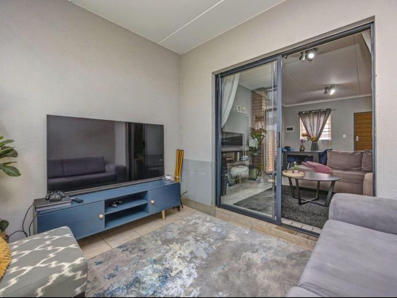 A comfortable living area featuring tiled flooring and a large sliding glass door that provides access to an adjacent room.
