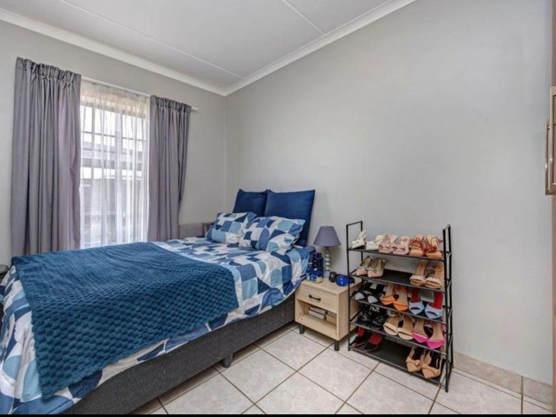 A functional bedroom featuring tiled flooring, neutral wall finishes, and a built-in wardrobe, offering a clean and practical living space.