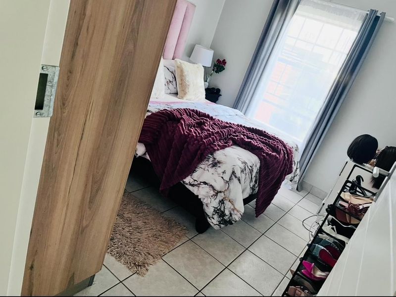A bedroom featuring tiled flooring and a window, viewed from the doorway.