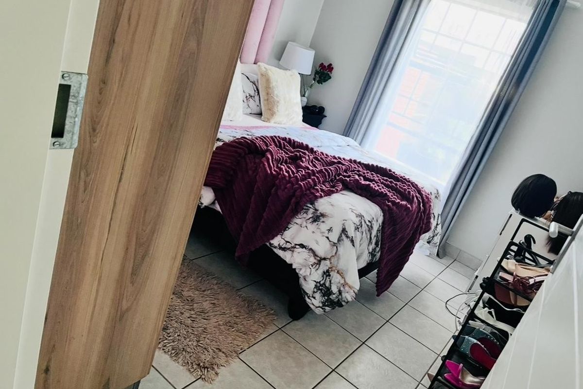A bedroom featuring tiled flooring and a window, viewed from the doorway.